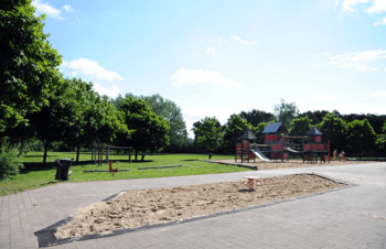 Spielplatz mit Holzhaus, Wiese und Sandkasten