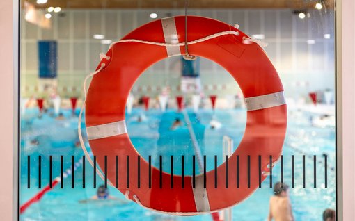 Ein orangener Rettungsring, durch den man ein Schwimmbad sieht