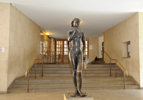 bronze Statue einer nackten Frau vor einer Treppe