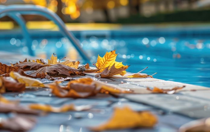 Detailausschnitt eines Beckenrands eines Pools mit Herbstlaub